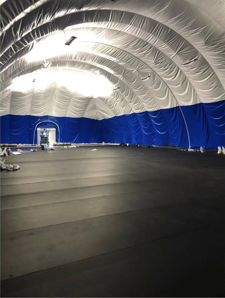 Interior of the air dome showing the clear span, blue lower liner, hanging light fixtures and rubber mat flooring